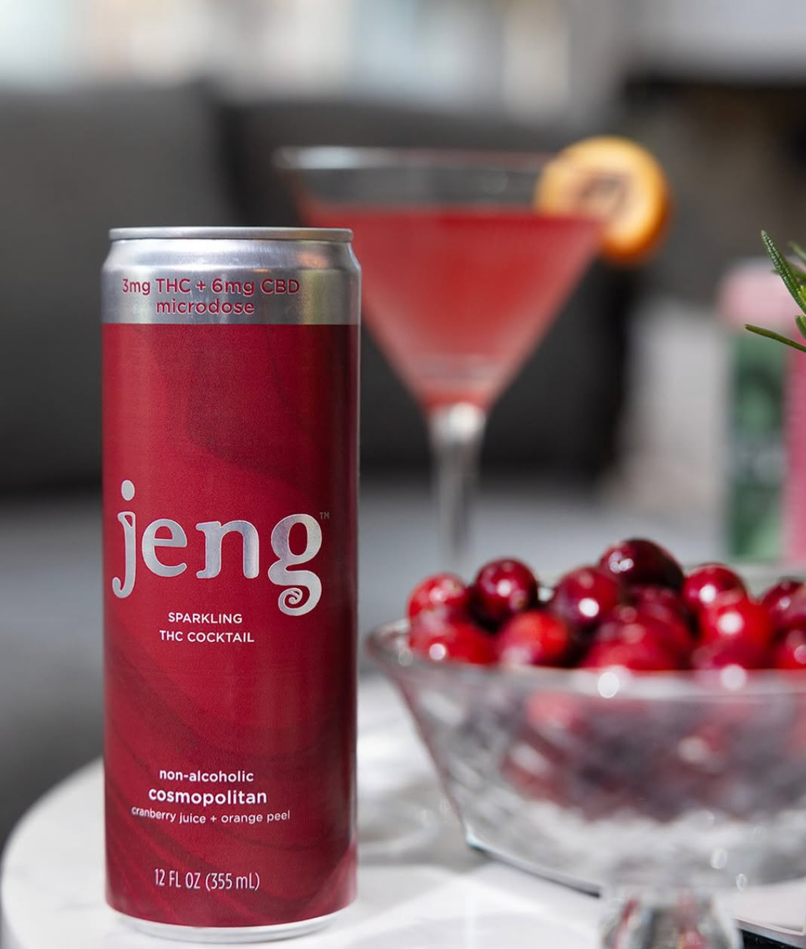 A red Jeng cosmopolitan microdose can beside a cocktail and cranberries